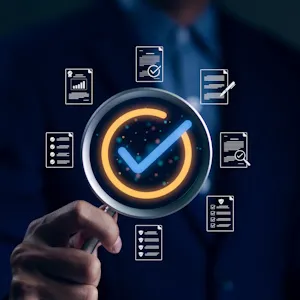 Checkmark inside a magnifying glass which is surrounded by business icons