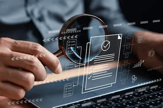 Hand holding magnifying glass over a laptop